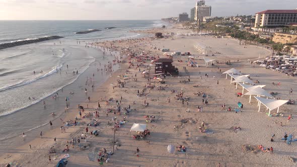 Aerial view of a sandy beach with people at sunset near the city of Herzelia in Israel