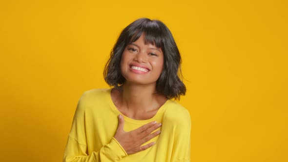 Close Up of Happy Sincere Young Dark Skinned Woman Laughs Out Yellow Background