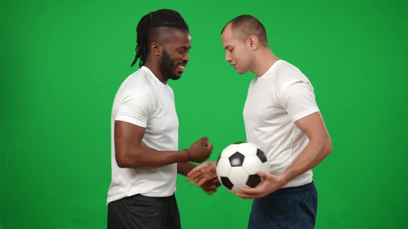 Side View Smiling African American Man Shaking Hands with Caucasian Teammate Passing Football Ball