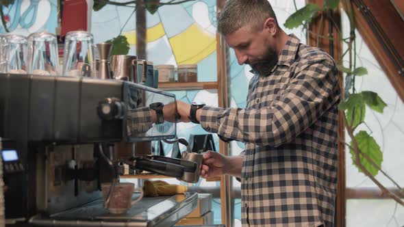 Barista heating up some milk while making coffee