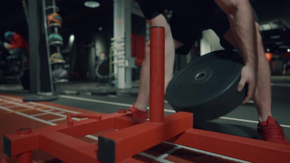 Man Putting Barbell Plate on Gym Stand