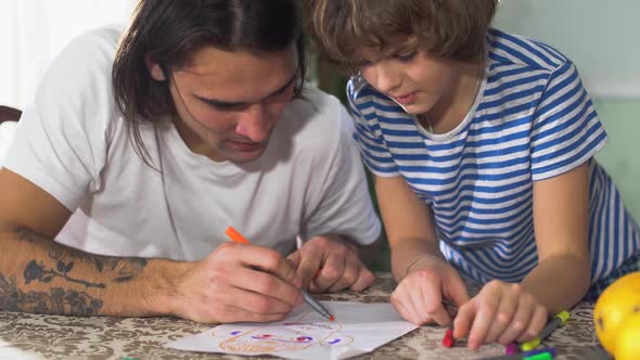 Two Brothers Drawing on Paper Sitting at the Table Together. Brothers Relationship