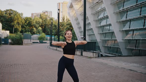 Energetic and Active Woman Trainer Leads a Dance Class in the Middle of a City Street