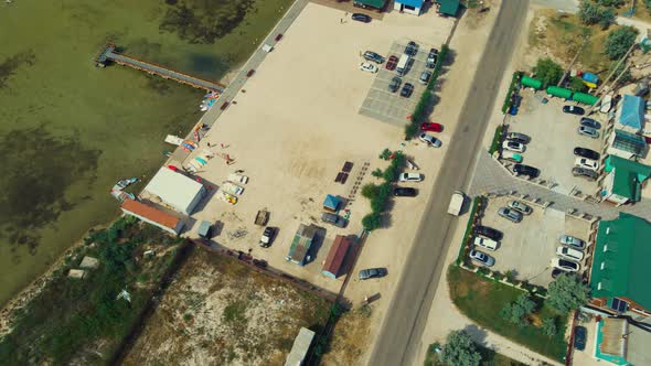 Drone Shot Surfing Station Area with Cars on Car Parking and Long Wooden Pier