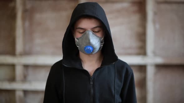 a teenager in a respirator looks at the floor, then raises his eyes