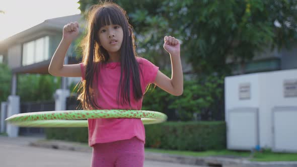 Young Asian little girl playing hulahoop exercise outdoor at home for health care and wellbeing.