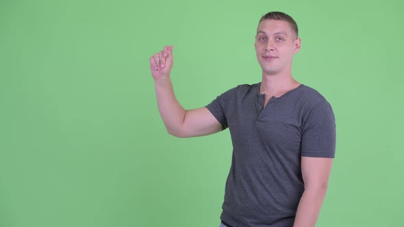Portrait of Happy Young Man Snapping Fingers and Showing Something