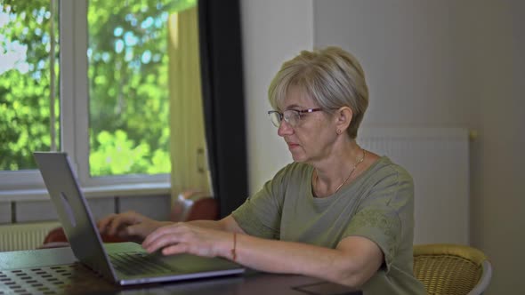Concentrated Aged Women with Poor Eyesight in the Glasses is Surfing Online