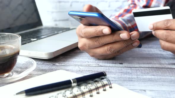 Man Hand Holding Credit Card Using Smart Phone Shopping Online on Office Desk