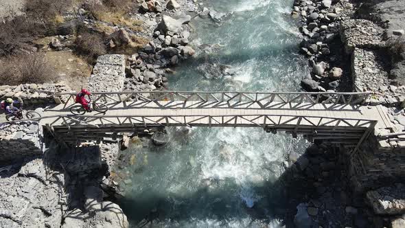 Two people riding mountain bikes on bridge over the Marsyangdi River