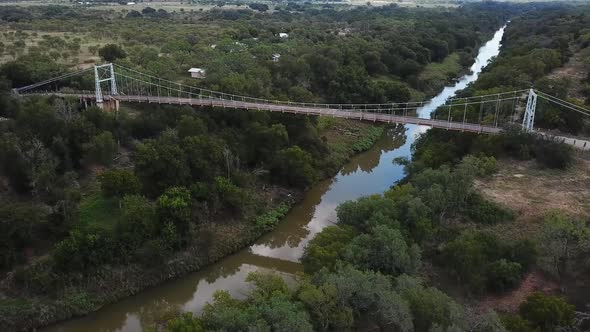 Old suspension bridge over river in rural Texas countryside.