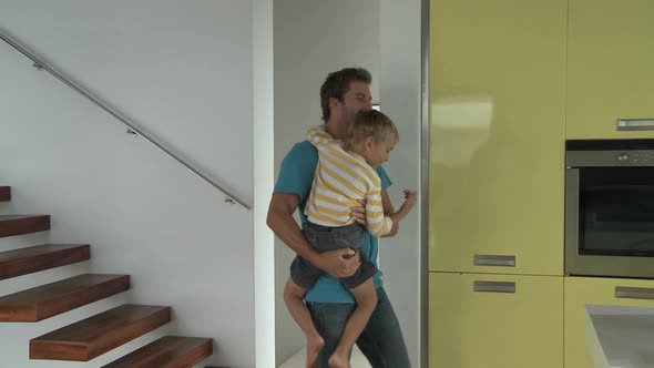 LS Tracking Left OF A MAN CARRYING HIS SON TO THE KITCHEN TO SEE A BIRTHDAY CAKE