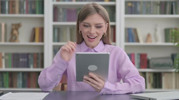 Woman Celebrating Success on Tablet in Office