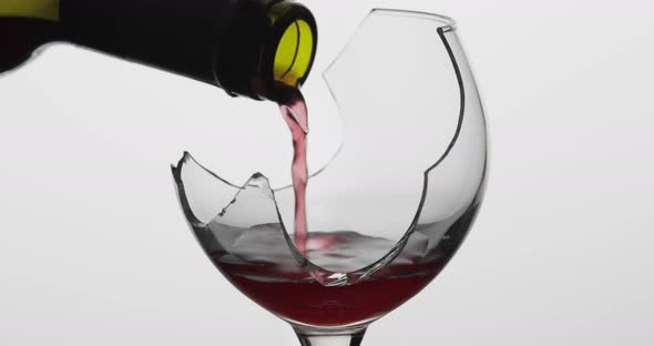 Wine. Red Wine Pouring in Broken Wine Glass on the White Background