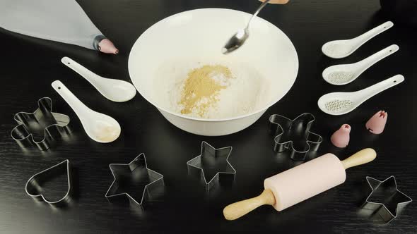 Female hand is adding ingredients to make spiced dough for gingerbread cookies