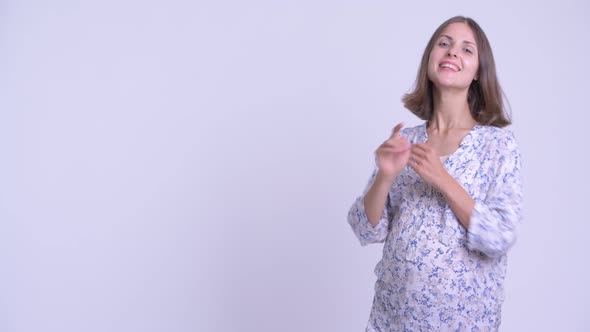 Happy Young Pregnant Woman Touching Something and Crossing Arms