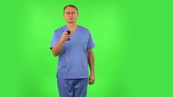 Medical Man with TV Remote in His Hand, Switching on TV. Green Screen