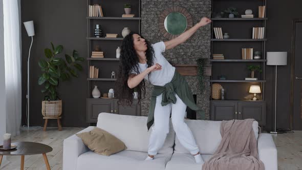 Young Attractive Fun Cute Joyful Woman Jumping on Sofa in Living Room Funny Dancing Actively