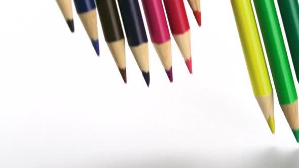 Color pencils falling on white paper, Slow Motion