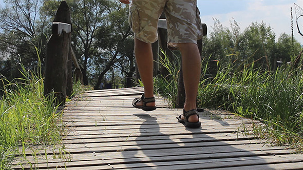 Man Steps Across a Footbridge