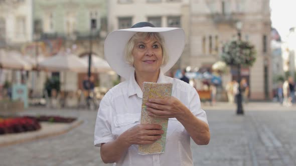 Senior Female Tourist Exploring Town with a Map in Hands. Looking for the Route