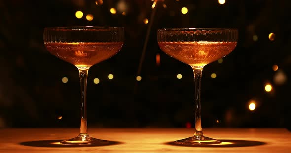 Two Glasses Of Champagne And Dark Background With Festive Gold Lights And New Year Sparkler.