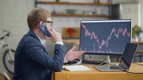 Young Broker Using Smartphone and Computers Working From Home