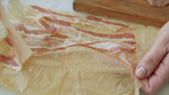 Woman shifting prosciutto from baking paper on plate