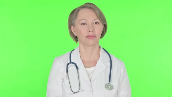 Denying Old Female Doctor Shaking Head to Stop on Green Background