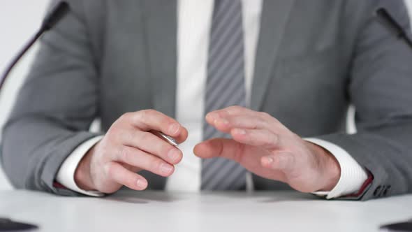 Man Wearing Grey Suit Gesticulating at Press Conference