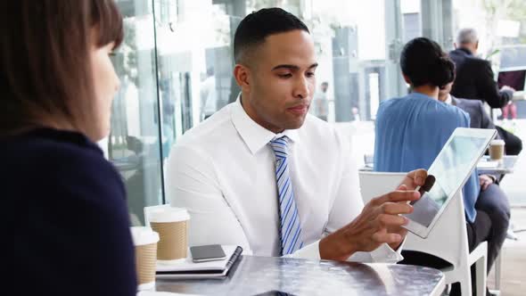 Businessman discussing over digital tablet with colleague