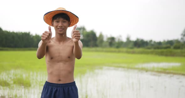 Young farmer topless standing and arms folded in rice field