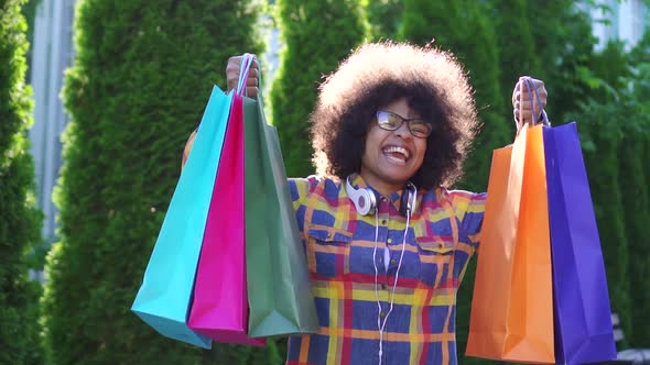 Portrait Cheerful African Woman with an Afro Hairstyle with Packages After Shopping Looking at the