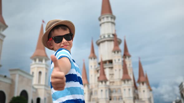 Child Boy Showing Thumb Up at Fairytale Castle of Amusement Park