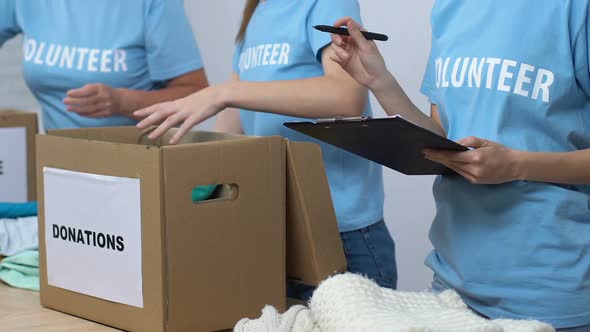Volunteers Packing Donated Clothes in Boxes, Supervisor Holding Check List, Care
