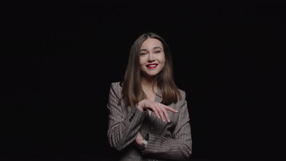 A stylish young brunette in a jacket mysteriously looks up and poses  a black background.