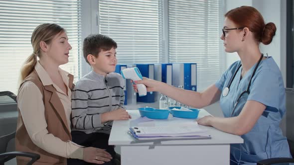 Portrait of Medical Doctor and Patients Therapist Measures the Temperature of Boy with Noncontact