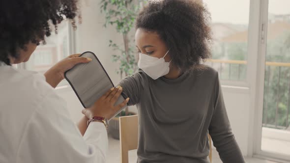 African american doctor is measuring blood pressure and checking pulse child patient.