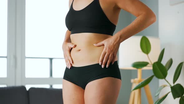 Woman Compressing the Skin on Her Stomach and Sides Checking for Cellulite and Excess Subcutaneous