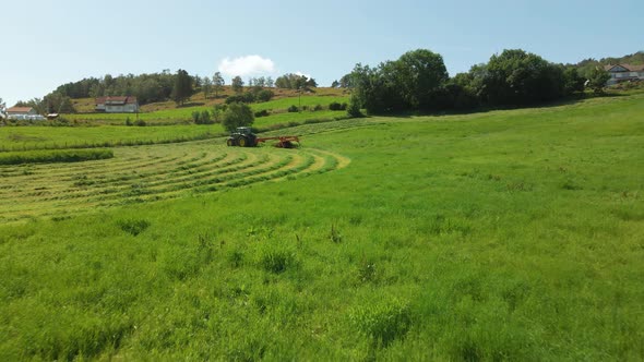 Tractor-drawn Forage Harvester Producing Silage On Green Field At Daytime. wide drone