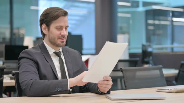 Businessman Celebrating Success While Reading Documents