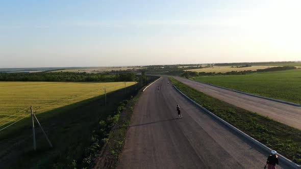 Teens Are Riding the Longboards on a Country Road at the Sunrise Film Grain