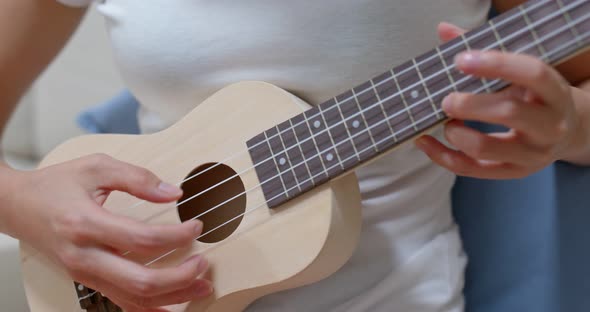 Woman pratice ukulele at home