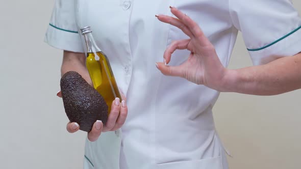 Nutritionist Doctor Holding Organic Avocado Fruit and Bottle of Oil