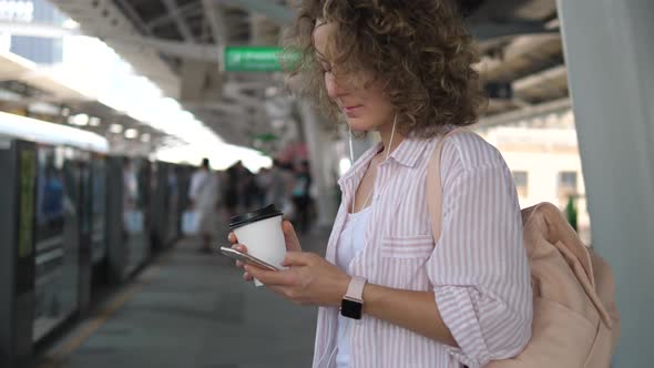 Female Commuter Using Mobile Phone While Waiting For Train