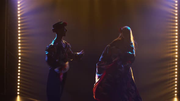 Silhouette Couple Dancers in Romany Clothes Dancing Merrily in Dark Studio Against Background of