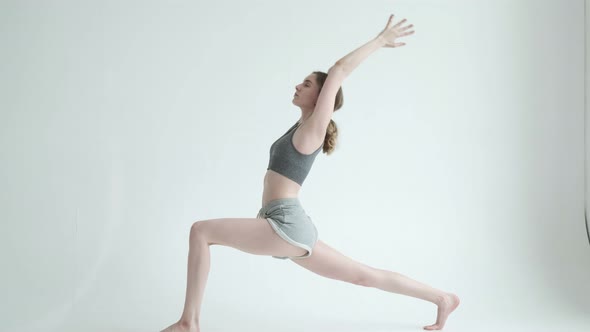 Young Slim Fit Girl Does Yoga Exercises in Bright Room