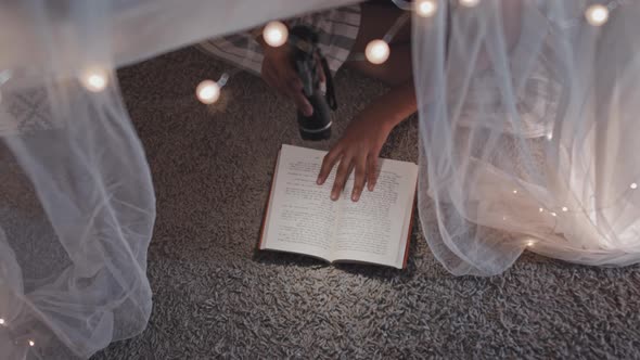 Child Reading Book on Floor at Night