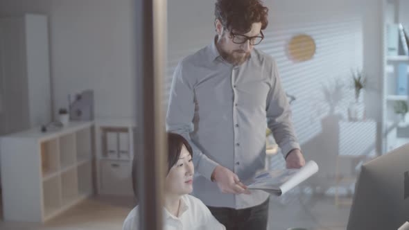 Man and Woman Checking Analytics in Dark Office