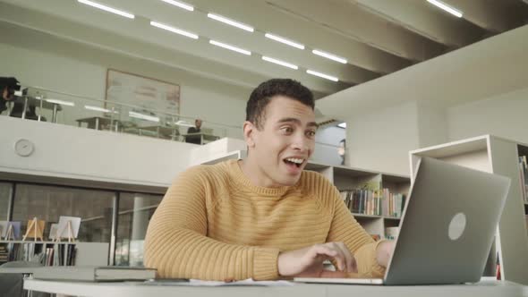 Excited Mixed Race Man Emotionally Rejoices at Success Near Laptop While Sitting at Workplace at